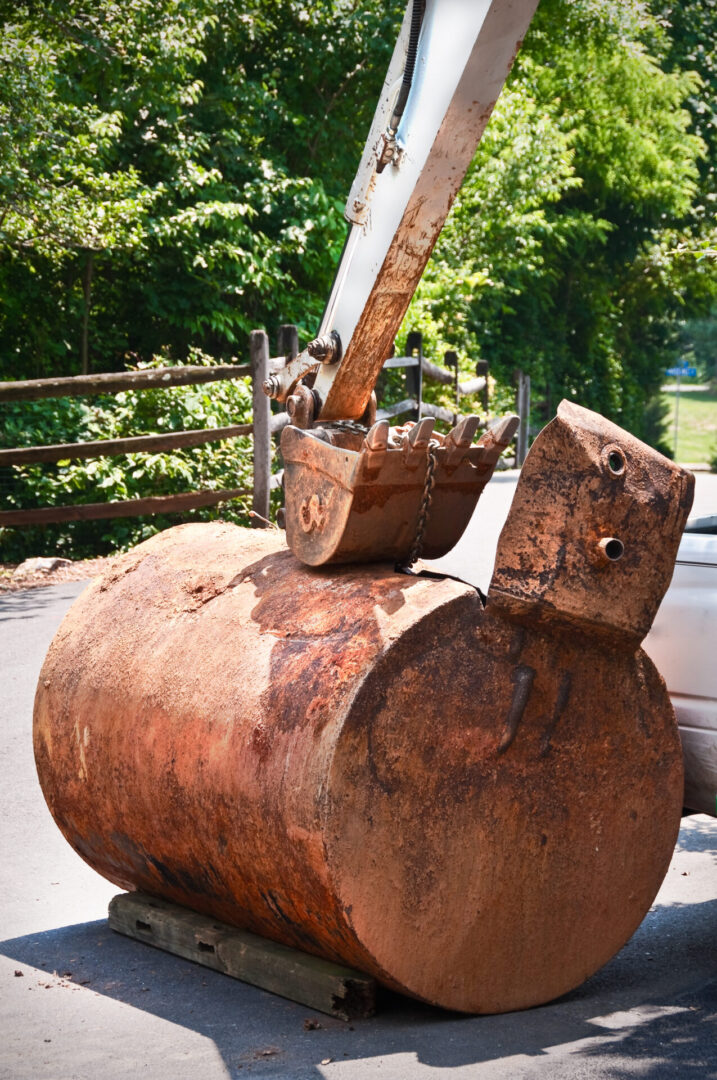 A large rusty tank sitting next to a tree.